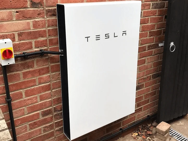 Tesla Powerwall battery storage unit mounted on an outside brick wall