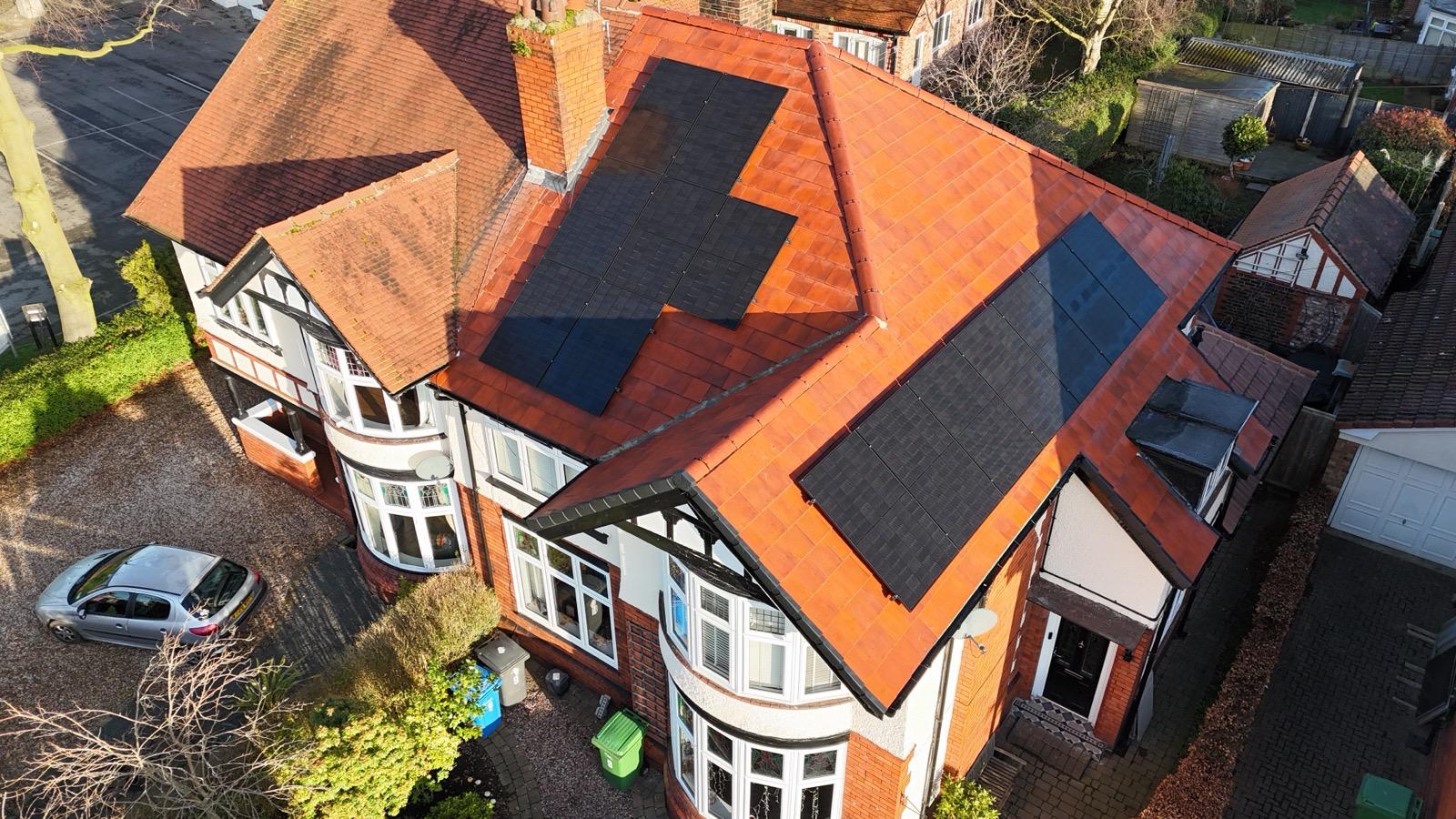 Black solar panels fitted across a red tiled residential roof