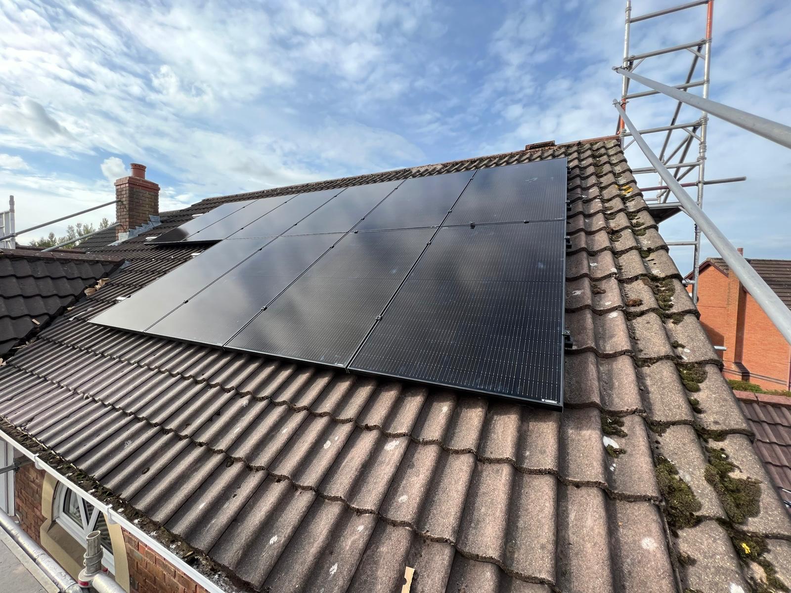 Solar panels mounted close to roof tiles with scaffolding beside the installation